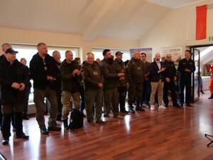 uczestnicy zgromadzeni na sali, osoba w mundurze przemawia do zebranych