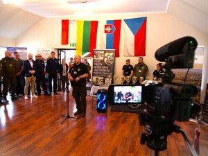 uczestnicy zgromadzeni na sali, osoba w mundurze przemawia do zebranych