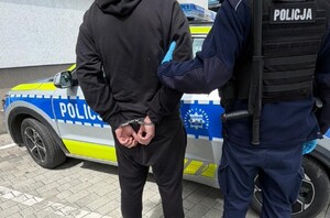 policjant prowadzi osobę zatrzymana, dzień