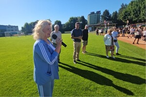 osoba przemawia do dzieci na stadionie, słonecznie