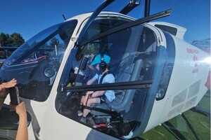 dziecko za sterami helikoptera stojącego na murawie stadionu