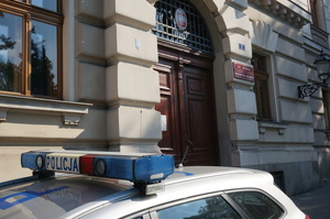 samochód policji, w tle budynek sądu, dzień
