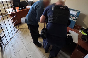 pomieszczenie, policjant i zatrzymany podpisują coś na kartce