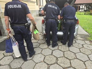 policjanci wnoszą torby do budynku domu dziecka