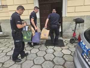 policjanci wnoszą torby do budynku domu dziecka