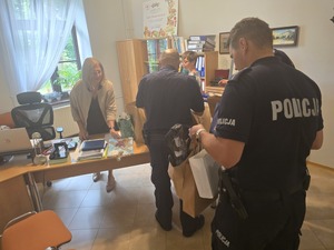 policjanci wnoszą torby do budynku domu dziecka