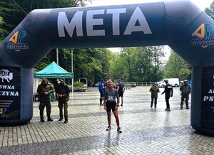 policjantka ubrana na sportowo, deszcz, za nią meta biegu