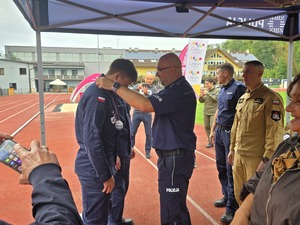 komendant i organizatorzy wręczają nagrody uczestnikom na stadionie, wszyscy uśmiechnięci