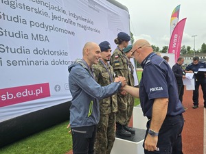 komendant i organizatorzy wręczają nagrody uczestnikom na stadionie, wszyscy uśmiechnięci