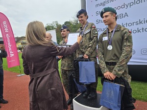 komendant i organizatorzy wręczają nagrody uczestnikom na stadionie, wszyscy uśmiechnięci