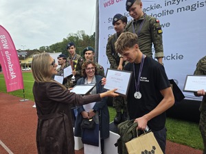 komendant i organizatorzy wręczają nagrody uczestnikom na stadionie, wszyscy uśmiechnięci