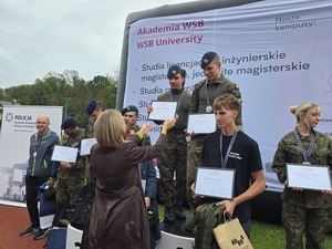 komendant i organizatorzy wręczają nagrody uczestnikom na stadionie, wszyscy uśmiechnięci