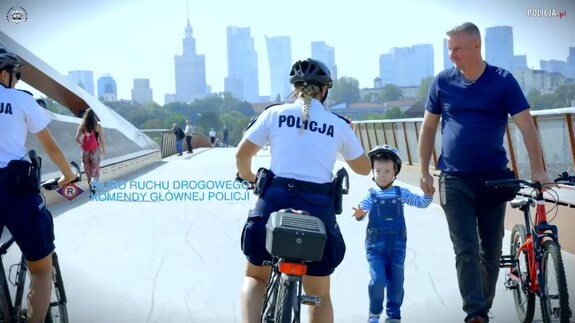 policjantka na rowerze, ojciec prowadzi dziecko za rękę, dzień