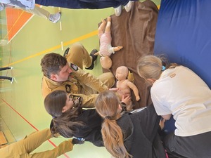 policjanci i ratownicy uczą udzielać dzieci pierwszej pomocy na manekinie- resuscytacja